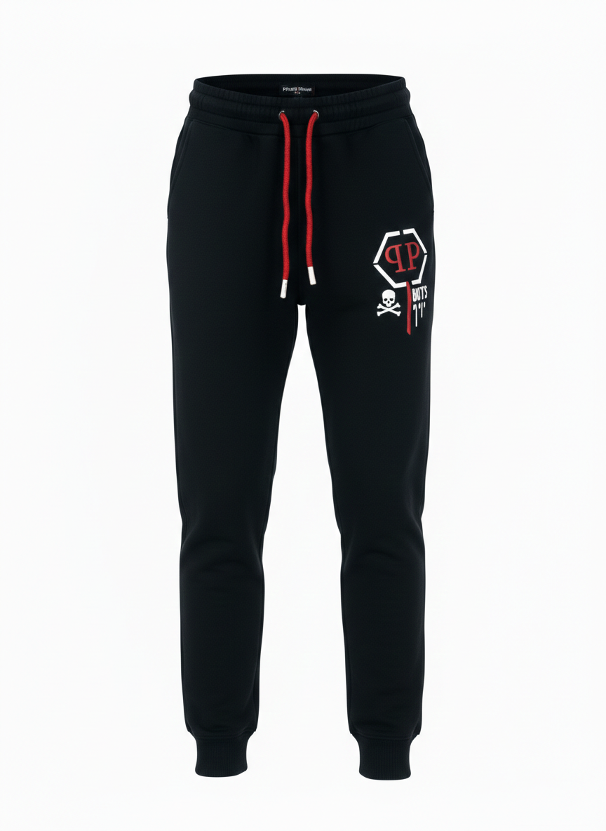 Front view of boys designer black joggers featuring a red drawstring, breathable athletic fabric, and a signature white skull graphic on the leg, available at Trendy Angels Boutique in Brunswick.