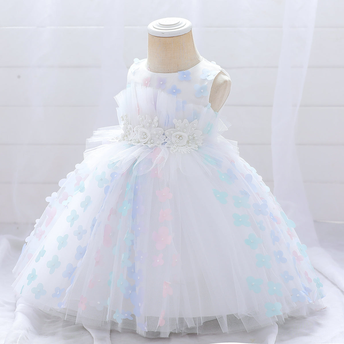 White girls' tulle dress with pastel floral appliques and pearl flower sash on mannequin