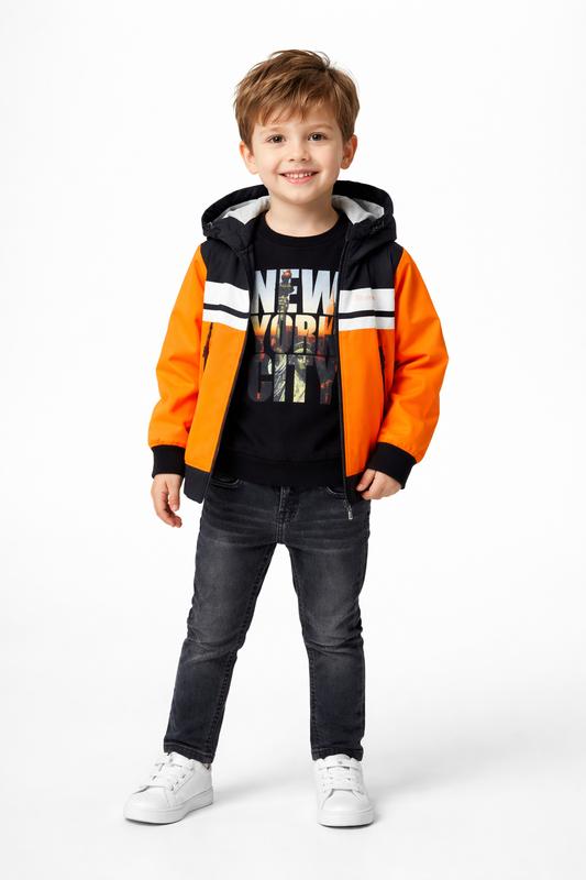 A young boy modeling a stylish NYC-themed winter outfit, featuring a vibrant orange and black hooded jacket paired with coordinated casual wear from Trendy Angels Boutique.