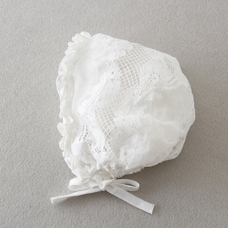 A close-up view of a traditional white full lace baby girl baptism bonnet with intricate floral patterns and a delicate ribbon tie, available at Trendy Angels Boutique, 533 Sydney Rd Brunswick Melbourne.