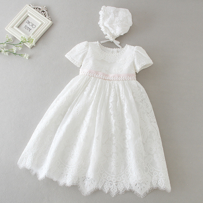 Front view of a baby girl’s white floral lace baptism dress with a pink ribbon waist displayed on a mannequin, available at 533 Sydney Rd, Brunswick