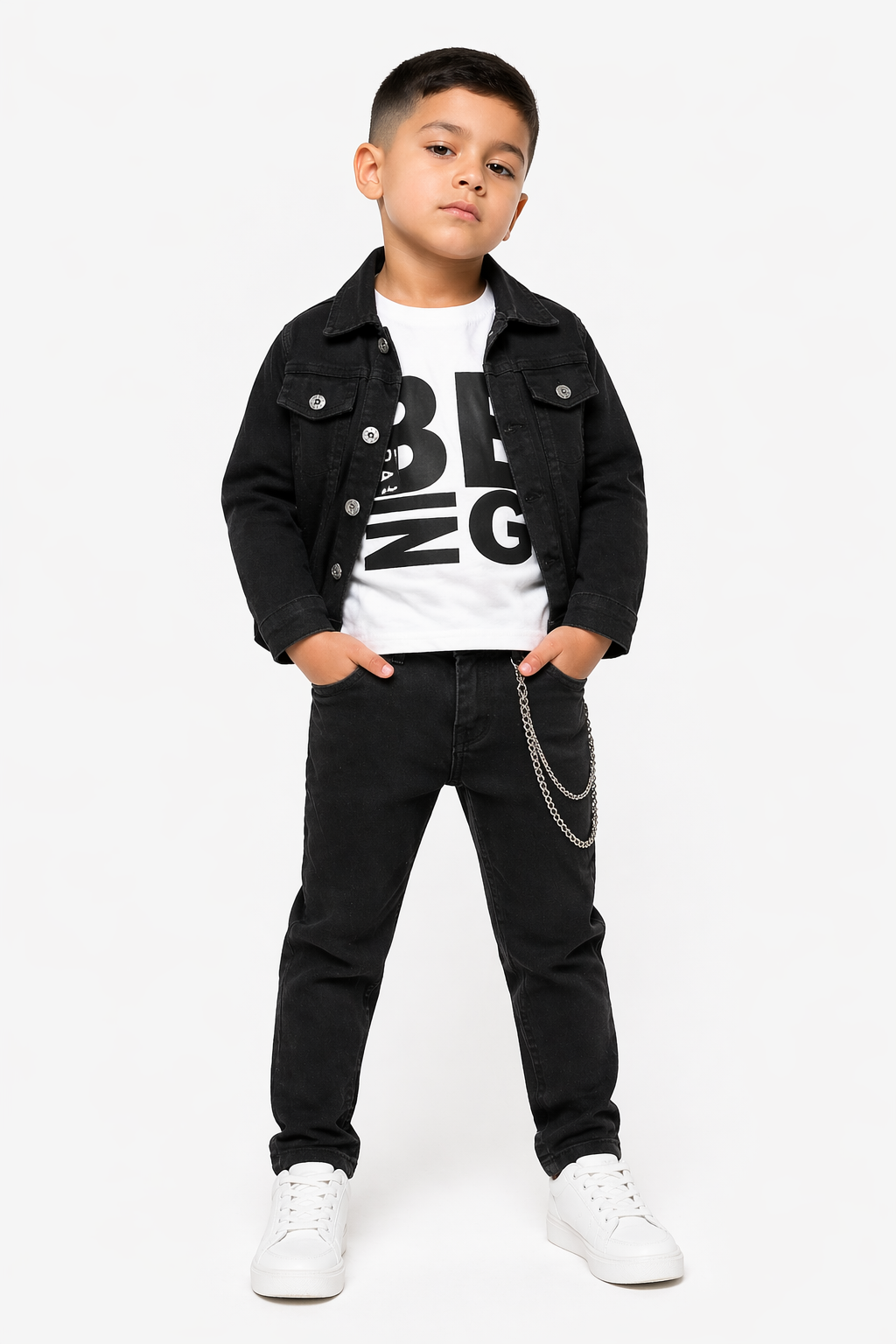 Young boy modeling the Exclusive Boys 3-Piece Black Denim Outfit, featuring a black denim jacket, white graphic t-shirt, and jeans with a wallet chain, from Trendy Angels Boutique.